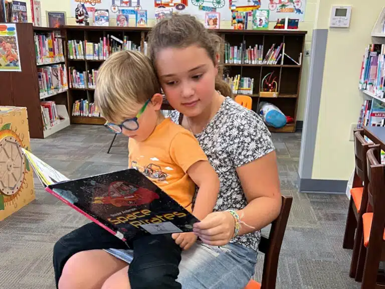 Siblings reading a book together at Casey County Public Library